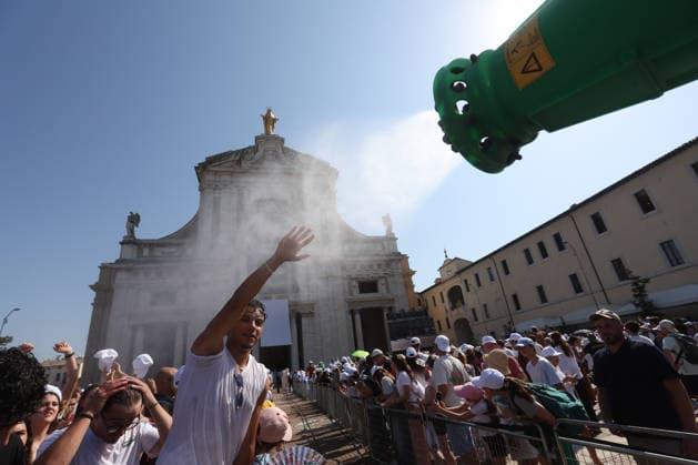 IPA87273186 - Assisi, Italy, August 6, 2026: Young people cool off under water jets due to the extreme heat. The Holy Father Leo XIV meets with young people participating in the GO! Franciscan Youth Meeting 2026 at the Basilica of Santa Maria degli Angeli in Assisi. The event brings together young people from various countries for a time of prayer, reflection, and sharing inspired by Franciscan spirituality.  Copyright: xmarcoxiacobuccix xmarcoxiacobuccix 87273186