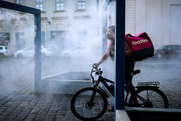 (260806) -- BUDAPEST, Aug. 6, 2026 -- A delivery man cools off under a misting system in Budapest, Hungary, Aug. 6, 2026. Hungarian authorities on Tuesday extended the country s highest-level heat alert until midnight on Friday as forecasts indicate the ongoing heatwave will continue across the country. (Photo by h Xinhua) HUNGARY-BUDAPEST-HEAT WAVE DavidxBalog 