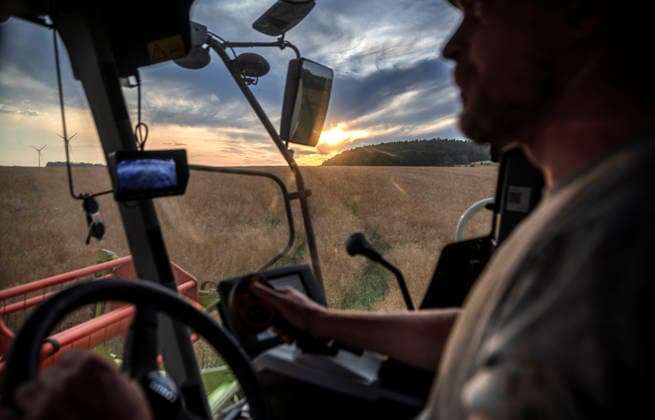 Nürnberg: Mähdrusch in der Dämmerung. - Ein Landwirt erntet mit seinem Mähdrescher vom Typ Claas Tucano ein großes Rapsfeld bei Burghaslach in Franken (Bayern) ab. Manchmal fällt sein Blick aus dem Führerstand auf romantische Sonnenuntergänge. Für die Ernte stehen in heißen Sommern oft nur wenige Tage zur Verfügung, die bis spät in die Nacht genutzt werden müssen. Nürnberg Bayern Deutschland *** Nuremberg: Combine Harvester at Dusk A farmer is harvesting a large rapeseed field near Burghaslach in Franconia, Bavaria, with his Claas Tucano combine harvester. Sometimes, from the driver’s cab, he catches a glimpse of romantic sunsets. During hot summers, there are often only a few days available for the harvest, which must be us