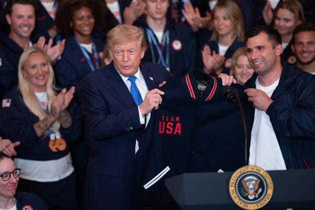 August 6, 2026, Washington, District Of Columbia, USA: United States President Donald J Trump is gifted a Team USA jacket and shoes in the East Room of the White House in Washington, DC, USA, on Thursday, August 6, 2026. President Trump is hosting a ceremony for Team USA Olympians who competed in the 2026 Olympic Winter Games in Italy Washington USA  - ZUMAs152 20260806_faa_s152_127 Copyright: xAaronxSchwartzx-xPoolxviaxCNPx