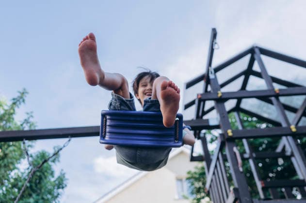 Happy boy laughing while playing on a swing outdoors model released, Symbolfoto, ANAF06472