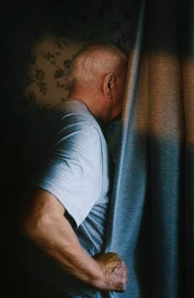 A man hides behind a curtain indoors at sunset model released, Symbolfoto, AZF01433