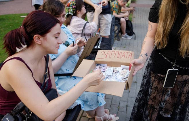 Activist Offers Souvenir Banknotes During Protest Against Dismissal Of Mykhailo Fedorov - Kyiv An activist holding a box signed Salary offers souvenir banknotes to those present as part of an ironic performance during an open-ended peaceful protest against the dismissal of Mykhailo Fedorov from the post of Ukraine s Defence Minister in Ivana Franka Square outside the Ivan Franko National Academic Drama Theatre, close to the Office of the President, Kyiv, Ukraine on August 6, 2026. Large-scale cardboard rallies in support of former Defence Minister Mykhailo Fedorov have been held in Kyiv and other cities across Ukraine for 22 consecutive days, following President Volodymyr Zelenskyy s dismissal of Fedorov on July 15, 2026, after the Ukra  Copyright: xUkrinform ABACAx