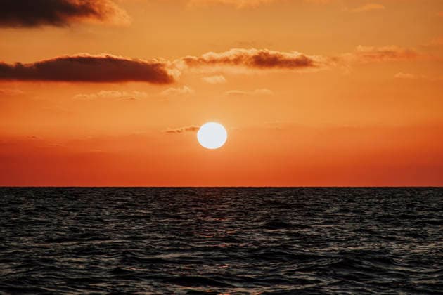 The bright sun sets over the calm ocean water, GMLF02273