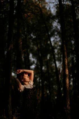Relaxed woman enjoys sunlight in a dark woodland environment model released, Symbolfoto, GMLF02294