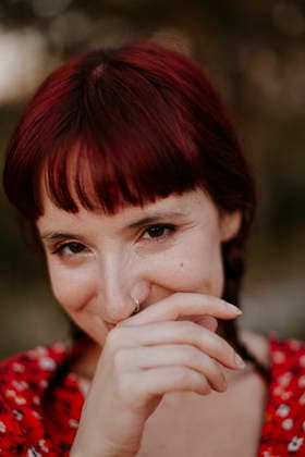 Smiling woman with red hair covering her mouth outdoors model released, Symbolfoto, GMLF02299