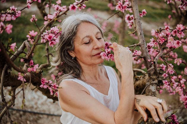 Woman smells pink flowers in a blossom orchard outdoors model released, Symbolfoto, GMLF02309