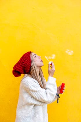 Woman in knit hat blowing bubbles against yellow background with copy space model released, Symbolfoto, JMHMF01426