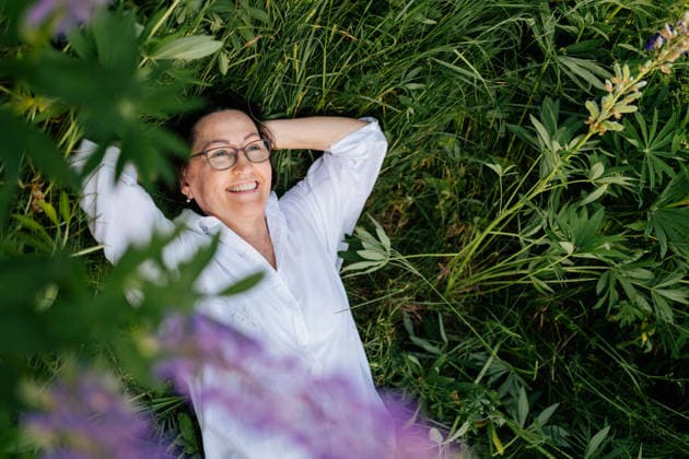A mature woman relaxes in green grass outdoors during summer vacation model released, Symbolfoto, MKVF00295