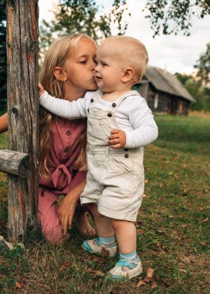 A young girl kisses her toddler brother outdoors in a rural yard model released, Symbolfoto, NASF00286