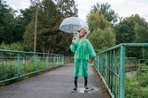 Happy woman in green raincoat jumps in a puddle on an outdoor bridge model released, Symbolfoto, OSF02776