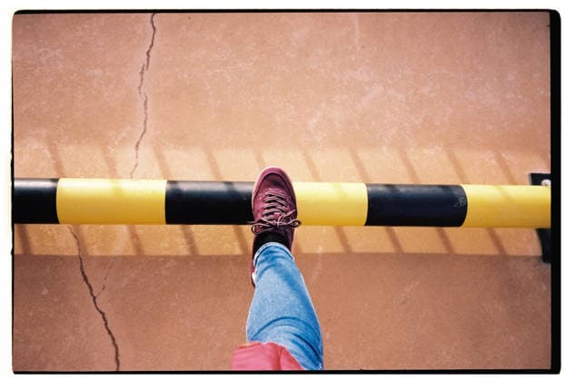 A person steps over a striped caution barrier outdoors model released, Symbolfoto, RDTF00667