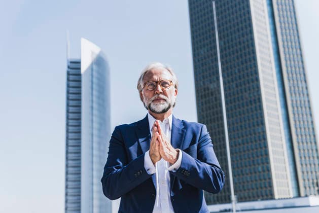 A businessman clasps his hands outside a corporate building model released, Symbolfoto, UUF37377
