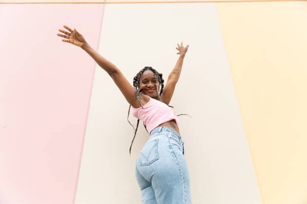 Happy woman jumps with arms raised against a pastel wall model released, Symbolfoto, YPF00346