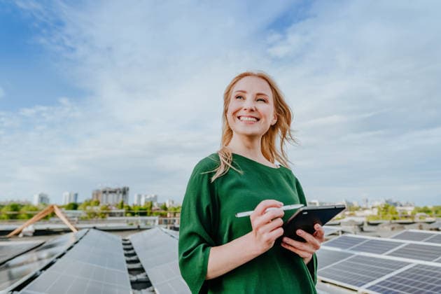 Smiling woman holds digital tablet near solar panel on roof outdoors model released, Symbolfoto property released, YTF04971