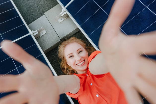 Smiling woman lies between solar panels reaching hands out model released, Symbolfoto property released, YTF05018