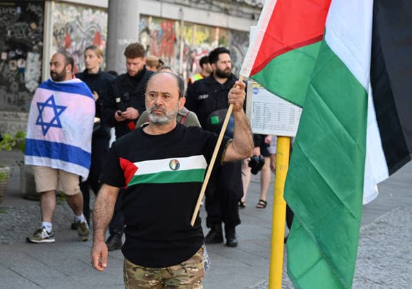 Pro-Palestinian rally in Berlin BERLIN, GERMANY - AUGUST 08: A man walks with an Israeli flag while police take security measures as protesters gather and march through the streets during a pro-Palestinian demonstration in Berlin, Germany, on August 08, 2026. Participants carried banners and flags to express solidarity with the Palestinian people and call for an immediate end to the war in Gaza. Volodymyr Sindieiev Anadolu Berlin Germany. Editorial use only. Please get in touch for any other usage.  Copyright: x2026xAnadoluxVolodymyrxSindieievx