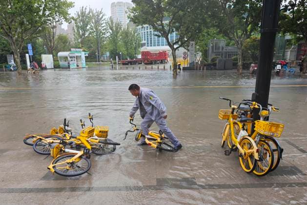 SHANGHAI, CHINA - AUGUST 09: Maintenance workers lift shared bicycles knocked over by wind and rain amidst accumulated water caused by Typhoon Dolphin on August 9, 2026 in Shanghai, China. The city experienced heavy rainfall and strong winds as Typhoon Dolphin made landfall.  Copyright: xVCGx 111659005866