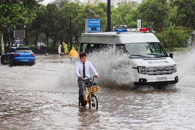 SHANGHAI, CHINA - AUGUST 09: Commuters ride shared bicycles through flooded streets on Lingling Road as Typhoon Dolphin brings heavy rainfall on August 9, 2026 in Shanghai, China. Public service personnel are patrolling and monitoring the situation across the city.  Copyright: xVCGx 111659005870