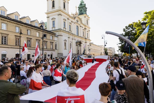 August 9, 2026, Warsaw, Poland: Participants hold a large Belarusian white-red-white national flag during an evening rally marking the sixth anniversary of the August 2020 presidential election in Belarus. An evening gathering marking the sixth anniversary of the August 2020 presidential election in Belarus was held near the Nicolaus Copernicus Monument in central Warsaw, bringing together leaders of Belarusian democratic forces, public figures and activists, as well as several hundred participants. Warsaw Poland - ZUMAs197 20260809_aaa_s197_106 Copyright: xVolhaxShukailax