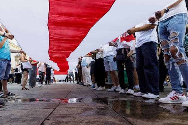 August 9, 2026, Warsaw, Poland: Participants carry a large white-red-white Belarusian flag during an evening rally marking the sixth anniversary of the August 2020 presidential election in Belarus. An evening gathering marking the sixth anniversary of the August 2020 presidential election in Belarus was held near the Nicolaus Copernicus Monument in central Warsaw, bringing together leaders of Belarusian democratic forces, public figures and activists, as well as several hundred participants. Warsaw Poland - ZUMAs197 20260809_aaa_s197_107 Copyright: xVolhaxShukailax
