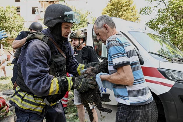 A firefighter hands a rescued cat to a man during a response effort to a Russian air strike, Zaporizhzhia, Ukraine, August 10, 2026. Russian forces attacked civilian infrastructure in the regional capital and the Zaporizhzhia district with guided aerial bombs. Apartment blocks and private houses were damaged, and cars were wrecked. At least 24 people were injured, including two children. (Photo by Dmytro Smolienko Ukrinform) Russian army attacks Zaporizhzhia with guided bombs again  Copyright: xDmytroxSmolienkox