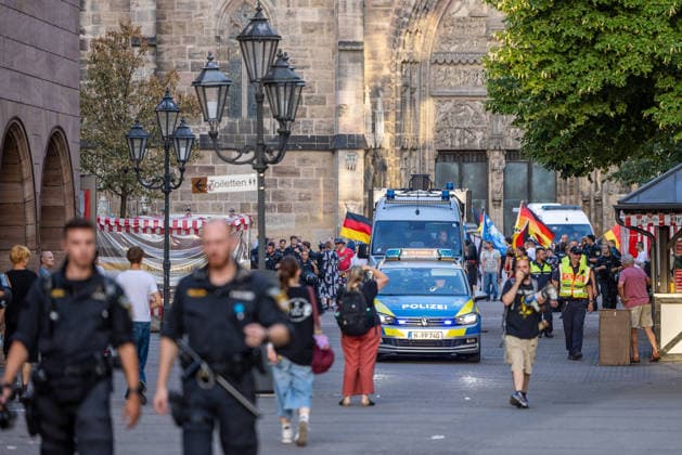 Polizeieinsatz bei Montagsdemo von Team Menschenrechte und Gegenprotesten, Nürnberg, 10.087.2026 Polizeikräfte begleiten einen Demonstrationszug von Team Menschenrechte und Gegenprotesten in der Karolinenstraße. Ein Einsatzfahrzeug der Polizei mit Blaulicht fährt inmitten von Demonstranten mit Deutschlandfahnen durch die Fußgängerzone. Nürnberg Bayern Deutschland *** Police operation during Monday demonstration by Team Menschenrechte and counter-protests, Nuremberg, 10 087 2026 Police officers escort a demonstration march by Team Menschenrechte and counter-protesters on Karolinenstraße. A police patrol car with its blue lights flashing drives through the pedestrian zone amid demonstrators carrying German flags. Nuremberg, Bavari 20260810-286A4960-M4000