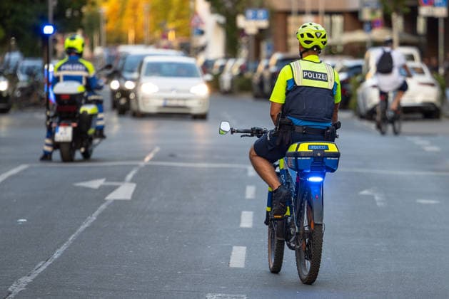 Polizeieinsatz bei Montagsdemo von Team Menschenrechte und Gegenprotesten, Nürnberg, 10.087.2026 Polizeibeamte auf Fahrrädern und Motorrad begleiten den Straßenverkehr während eines Einsatzes. Ein Fahrradstreife mit Blaulicht fährt im Verkehr mit, im Hintergrund folgt ein weiterer Beamter auf einem Polizeimotorrad. Nürnberg Bayern Deutschland *** Police operation during the Monday demonstration by Team Menschenrechte and counter-protests, Nuremberg, 10 087 2026 Police officers on bicycles and motorcycles direct traffic during an operation. A bicycle patrol with its blue lights flashing rides through traffic, while another officer on a police motorcycle follows in the background. Nuremberg, Bavaria, Germany 20260810-286A5017-M4000