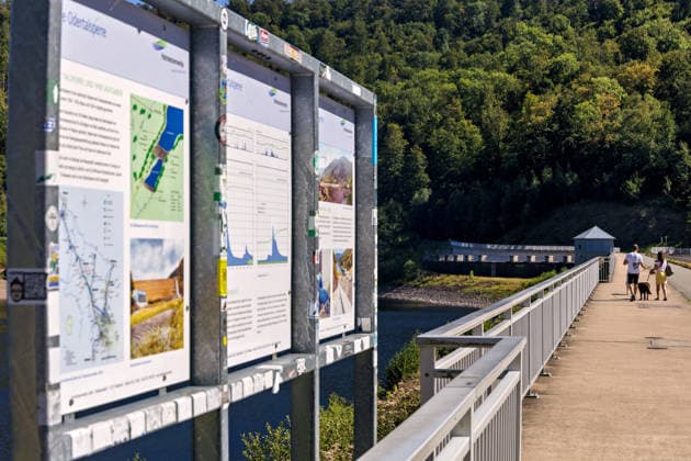 12.08.2026 Blick auf die Staumauer der Odertalsperre von Bad Lauterberg im Landkreis Göttingen in Niedersachsen. Besucher und Touristen gehen auf der Staumauer spazieren. Sie ist die südlichste Talsperre der Harzwasserwerke und wurde in den Jahren 1930 - 1933 erbaut und 1934 in Betrieb genommen. Mit einem Staudamm von 310 Meter Länge bietet die Talsperre vor allem Hochwasserschutz für die Region um Bad Lauterberg und kann bis zu 30,6 Millionen m3 Wasser speichern. Neben dem Hochwasserschutz gibt die Talsperre bei der Niedrigwassererhöhung außerdem Wasser an Unterlauf der Oder ab und schützt damit Flora und Fauna im Lebensraum Fluss. Bad Lauterberg Niedersachsen Deutschland *** August 12, 2026: View of the dam at the Odertal Reserv
