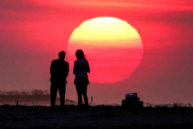 August 12, 2026, Isle Of Palms, Sc, United States: A couple silhouetted by the sunrise, stop to watch as the massive ball climbs over the Atlantic Ocean horizon, August 12, 2026 in Isle of Palms, South Carolina. The Charleston area is currently under a heat advisory with temperatures in the 90Ã¢â‚¬â ¢s and a heat index of 115-degrees. Isle Of Palms United States  - ZUMAe02_ 20260812_zaf_e02_003 Copyright: xRichardxEllisx