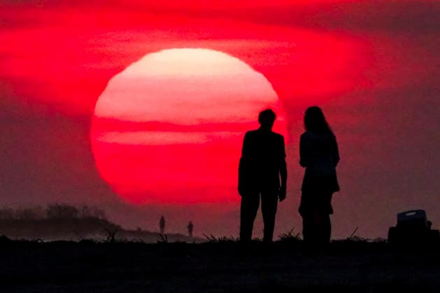 August 12, 2026, Isle Of Palms, Sc, United States: A couple silhouetted by the sunrise, stop to watch as the massive ball climbs over the Atlantic Ocean horizon, August 12, 2026 in Isle of Palms, South Carolina. The Charleston area is currently under a heat advisory with temperatures in the 90Ã¢â‚¬â ¢s and a heat index of 115-degrees. Isle Of Palms United States - ZUMAe02_ 20260812_zaf_e02_002 Copyright: xRichardxEllisx