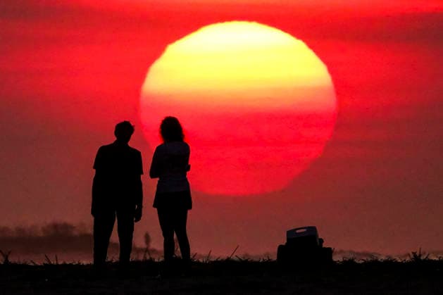August 12, 2026, Isle Of Palms, Sc, United States: A couple silhouetted by the sunrise, stop to watch as the massive ball climbs over the Atlantic Ocean horizon, August 12, 2026 in Isle of Palms, South Carolina. The Charleston area is currently under a heat advisory with temperatures in the 90Ã¢â‚¬â ¢s and a heat index of 115-degrees. Isle Of Palms United States - ZUMAe02_ 20260812_zaf_e02_004 Copyright: xRichardxEllisx