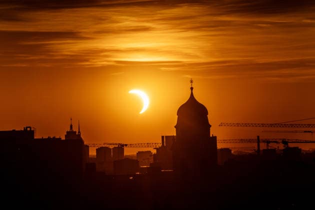 Partielle Sonnenfinsternis kurz nach ihrem Höhepunkt um 20:24 Uhr, Sonnensichel versinkt hinter dem Horizont neben dem Kirchturm von St. Wolfgang, Stadtteil Haidhausen, München, 12. August 2026 Deutschland, München, 12. August 2026, partielle Sonnenfinsternis kurz nach ihrem Höhepunkt um 20:24 Uhr, Sonnensichel versinkt neben dem markanten Zwiebelturm von St. Wolfgang in Haidhausen, der Mond schiebt sich vor die tiefstehende Sonne und deckt sie zu 89 Prozent ab, Sonnensichel kurz vor dem Sonnenuntergang um 20:32 Uhr, der Münchner Abendhimmel leuchtet in Orange, Blick von einem Hochhaus an der Rosenheimer Straße stadteinwärts, die katholische Pfarrkirche St. Wolfgang wurde 1920 eingeweiht, Astronomie, Sommer, Bayern, bayerisch, *** Pa