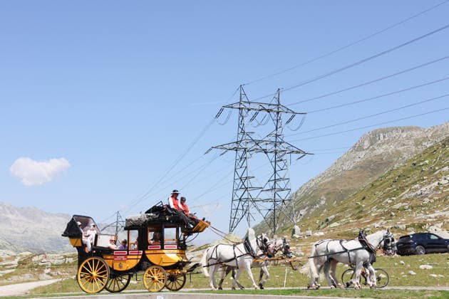 13.08.2026 Schweiz Nostalgie Postkutsche. Bild, Gotthardpost, Historische Postkutschenfahrt von Andermatt ueber den Gotthardpass ueber die Tremolastrasse nach Airolo . Vorbei an einem Hochspannungsmast. *** August 13, 2026 Switzerland Nostalgic Stagecoach Photo, Gotthard Post, Historic stagecoach ride from Andermatt over the Gotthard Pass via the Tremola Road to Airolo, passing a high-voltage power pole 