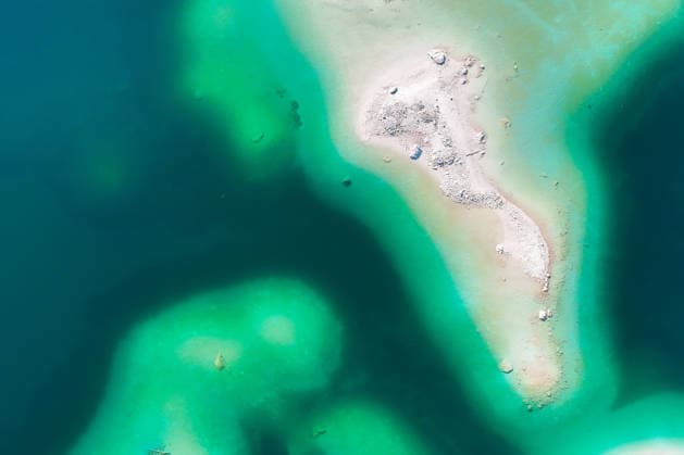Wetterfeature, Morgenstille am Eibsee: Unterhalb der Zugspitze liegt der See bei Grainau nahe Garmisch-Partenkirchen in den frühen Stunden noch ruhig und nahezu unberührt. Doch an heißen Sommertagen ändert sich das Bild häufig schon ab Mittag. Dann strömen zahlreiche Ausflügler und Urlauber an den durch soziale Medien weltweit bekannt gewordenen Bergsee. Der zunehmende Massentourismus sorgt regelmäßig für einen regelrechten Besucheransturm. Unter dem hohen Verkehrsaufkommen, zugeparkten Straßen und dem großen Andrang leiden zunehmend auch die Anwohner in Grainau und rund um den Eibsee. (Aufnahme mit einer Drohne) Grainau Bayern Deutschland Grainau *** Weather Feature, Morning Stillness at Eibsee. Nestled below the Zugspitze near Copyright: x xonw-imagesx xMariusxBullingx