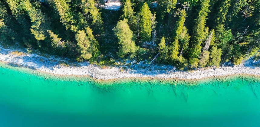 Wetterfeature, Morgenstille am Eibsee: Unterhalb der Zugspitze liegt der See bei Grainau nahe Garmisch-Partenkirchen in den frühen Stunden noch ruhig und nahezu unberührt. Doch an heißen Sommertagen ändert sich das Bild häufig schon ab Mittag. Dann strömen zahlreiche Ausflügler und Urlauber an den durch soziale Medien weltweit bekannt gewordenen Bergsee. Der zunehmende Massentourismus sorgt regelmäßig für einen regelrechten Besucheransturm. Unter dem hohen Verkehrsaufkommen, zugeparkten Straßen und dem großen Andrang leiden zunehmend auch die Anwohner in Grainau und rund um den Eibsee. (Aufnahme mit einer Drohne) Grainau Bayern Deutschland Grainau *** Weather Feature, Morning Stillness at Eibsee. Nestled below the Zugspitze near Copyright: x xonw-imagesx xMariusxBullingx