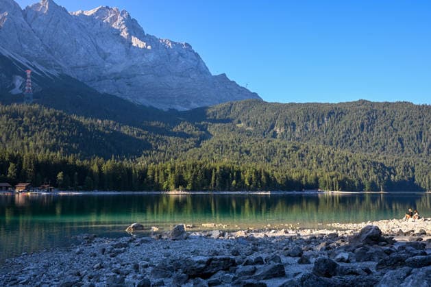 Wetterfeature, Morgenstille am Eibsee: Unterhalb der Zugspitze liegt der See bei Grainau nahe Garmisch-Partenkirchen in den frühen Stunden noch ruhig und nahezu unberührt. Doch an heißen Sommertagen ändert sich das Bild häufig schon ab Mittag. Dann strömen zahlreiche Ausflügler und Urlauber an den durch soziale Medien weltweit bekannt gewordenen Bergsee. Der zunehmende Massentourismus sorgt regelmäßig für einen regelrechten Besucheransturm. Unter dem hohen Verkehrsaufkommen, zugeparkten Straßen und dem großen Andrang leiden zunehmend auch die Anwohner in Grainau und rund um den Eibsee. Grainau Bayern Deutschland Grainau *** Weather Feature, Morning Stillness at Eibsee. Nestled below the Zugspitze near Grainau, close to Garmisch- Copyright: x xonw-imagesx xMariusxBullingx