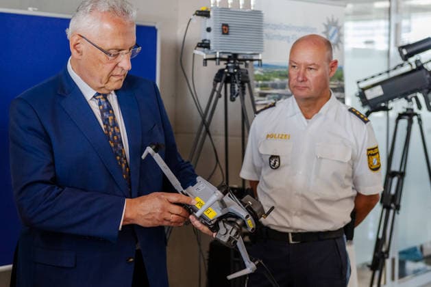 Innenminister Herrmann informiert über Drohnendetektion und -abwehr der Bayerischen Polizei, Flughafen Nürnberg, 14.08.2026 Ein Innenminister lässt sich technisches Gerät zur Drohnendetektion und -abwehr der Bayerischen Polizei erläutern, während ein Polizeibeamter in Uniform daneben steht. Im Hintergrund sind weitere technische Ausrüstung sowie ein Teleskop zu sehen. Die Bayerische Polizei stellt Möglichkeiten zum Ausbau von Technik und Personal sowie zur Verstärkung der Grenzpolizeiinspektion vor. Nürnberg Flughafen Bayern Deutschland *** Interior Minister Herrmann Provides Information on the Bavarian Police’s Drone Detection and Defense Systems, Nuremberg Airport, August 14, 2026 An interior minister is being briefed on the Bav 20260814-286A5360-M4000