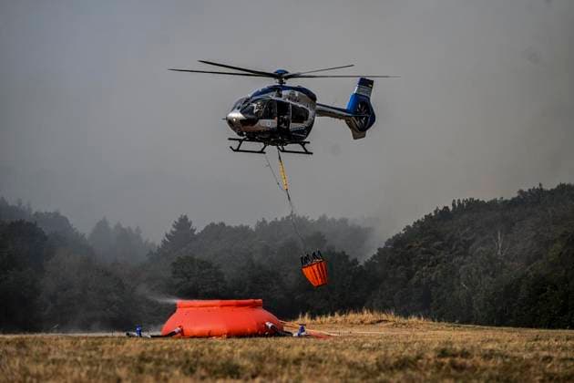 Waldbrände im Kreis Düren in der Eifel Hürtgenwald ** NUR FÜR REDAKTIONELLE ZWECKE ** EDITORIAL USE ONLY **<p>Hubschrauber im Dauereinsatz, beladen ihre Wassertanks in Großhau auf einem Feld , im Hintergrund Rauch vom Waldbrand , am Freitag, dem 14 08 2026 Waldbrände im Kreis Düren in der Eifel Hürtgenwald Deutschland NRW Essen Copyright: KerstinxKokoska *** Forest fires in the Düren district in the Eifel region, Hürtgenwald ** FOR EDITORIAL USE ONLY ** ** EDITORIAL USE ONLY ** Helicopters in continuous operation are filling their water tanks in a field in Großhau, with smoke from the forest fire visible in the background, on Friday, August 14, 2026. Forest fires in the Düren district in the Eifel region, Hürtgenwald, Germa Copyright: KerstinxKokoska doc875prs435w9wl3c4lcl ,EDITORIAL USE ONLY