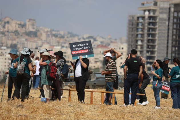 Activists Remove Flags From Beit Sahour Activists gather near a wooden ladder while holding placards and flags in Beit Sahour, east of Bethlehem in the occupied West Bank, on August 14, 2026. The activists said settlers had placed the symbols on the house after October 7, 2023, in what they described as an attempt to seize control of the property, and that settlers opened fire toward them as the items were removed, with no injuries reported. Bethlehem West Bank Palestinian Territories Copyright: xMosabxShawerx