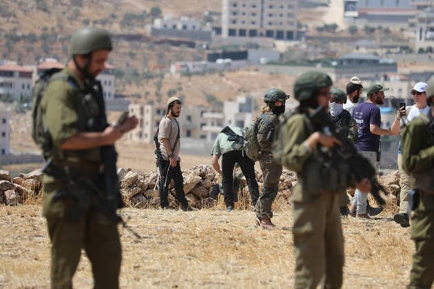 Activists Remove Flags From Beit Sahour Uniformed security personnel stand in the foreground as armed men and activists remain farther back in Beit Sahour, east of Bethlehem in the occupied West Bank, on August 14, 2026. The activists said settlers had placed the symbols on the house after October 7, 2023, in what they described as an attempt to seize control of the property, and that settlers opened fire toward them as the items were removed, with no injuries reported. Bethlehem West Bank Palestinian Territories Copyright: xMosabxShawerx