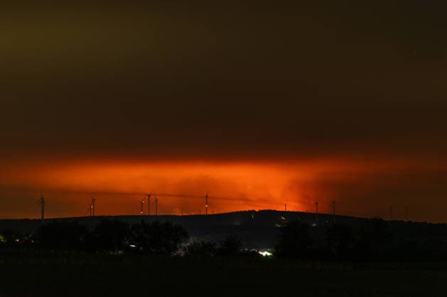 Nachtaufnahme: Waldbrand im Hohen Venn hinter Windkrafträdern bei Kleinhau Nachtaufnahme aus Kleinhau (Gemeinde Hürtgenwald): Am Horizont, rund 26 Kilometer entfernt in Belgien, erhellt rötlicher Flammenschein den Brandrauch des Großbrands im Hohen Venn bei Drossart (Gemeinde Baelen) dort ist die Fläche seit dem Nachmittag von rund 1 auf etwa 80 Hektar gewachsen, ein Notfallplan der Provinz Lüttich wurde ausgerufen. Im Vordergrund sind Windkrafträder zu erkennen. Hürtgenwald Kleinhau Nordrhein-Westfalen Deutschland *** Night shot of a forest fire in the High Fens behind wind turbines near Kleinhau. Night shot taken from Kleinhau, in the municipality of Hürtgenwald. On the horizon, about 26 kilometers away in Belgium, a reddish g Copyright: xMarcxJohnx
