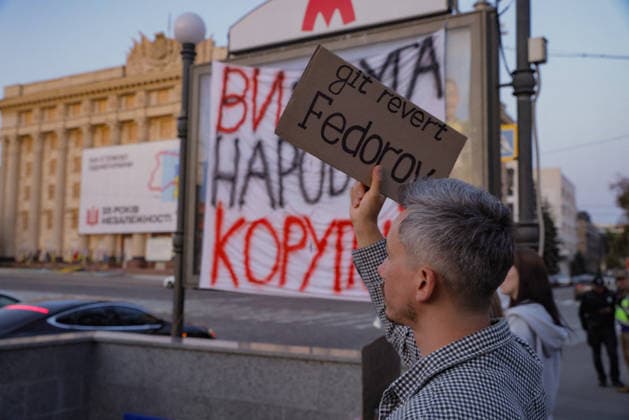 Kharkiv Protesters Demand Reinstatement of Defence Minister Fedorov - Ukraine A protester holds a cardboard sign reading git revert Fedorov — a software development metaphor calling for the reinstatement of Mykhailo Fedorov as Minister of Defence — at Freedom Square in Kharkiv, Ukraine, on August 14, 2026. In the background, a large banner reads ?? ?????? ???????? ( You gave the people corruption ), hung beneath the Universytet metro station sign. Participants gathered for a rally demanding Fedorov s return, part of nationwide demonstrations against President Zelensky s decision to dismiss him. Photo by Yevhen Titov ABACAPRESS.COM Kharkiv Kharkiv Oblast Ukraine  Copyright: xTitovxYevhen ABACAx
