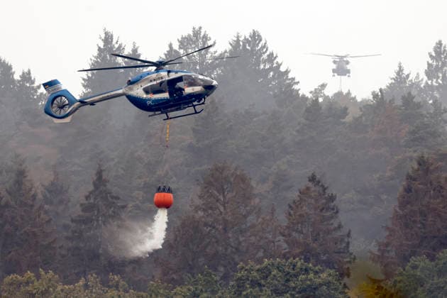 Hubschrauber von Bundeswehr und Bundespolizei, Bergepanzer der Bundeswehr und zahlreiche Kräfte von Feuerwehr und anderen Freiwilligen sind beim Waldbrand im Hürtgenwald im Einsatz. Mehrere Hundert Hektar Waldfläche stehen in Flammen, die Feuerwalze hat sich bis dicht an einzelne Stadtteile herangefressen. Bauern und Helfer bringen immer wieder neue Wassertanks heran. Wegen der anhaltenden Hitzewelle sind die Wälter extrem trocken. Hürtgenwald, 15.08.2026 NRW Deutschland *** Helicopters from the German Armed Forces and the Federal Police, armored recovery vehicles from the German Armed Forces, and numerous firefighters and other volunteers are on the scene of the wildfire in the Hürtgenwald. Several hundred hectares of forest are ablaz Copyright: xChristophxHardtx