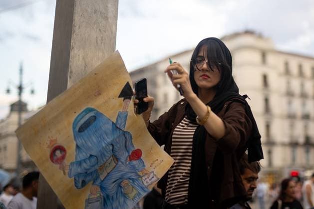 August 15, 2026, Madrid, Spain: A woman carries a banner with a cartoon depicting an Afghan woman wearing a burqa during a rally in Madrid s Puerta del Sol, Afghan women asylum seekers and feminist groups gathered to commemorate the five-year anniversary of the Taliban s return to power in Afghanistan, following the withdrawal of US and NATO troops and the resulting setbacks in human rights and the rise of gender apartheid. Madrid Spain - ZUMAs197 20260815_aaa_s197_095 Copyright: xDavidxCanalesx