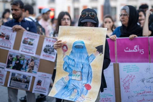 August 15, 2026, Madrid, Spain: A woman carries a banner with a cartoon depicting an Afghan woman wearing a burqa during a rally in Madrid s Puerta del Sol, Afghan women asylum seekers and feminist groups gathered to commemorate the five-year anniversary of the Taliban s return to power in Afghanistan, following the withdrawal of US and NATO troops and the resulting setbacks in human rights and the rise of gender apartheid. Madrid Spain - ZUMAs197 20260815_aaa_s197_102 Copyright: xDavidxCanalesx