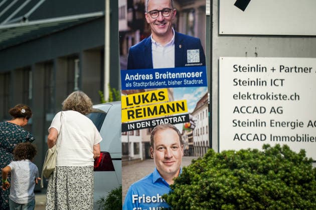 Schweiz: Politik, Wahlkampf in Wil (SG); Wahlplakate von Andreas Breitenmoser (Die Mitte) als Kandidat für das Stadtpräsidium und Lukas Reimann (SVP) als Kandidat für den Stadtrat vor dem zweiten Wahlgang am 16. August 2026. Passantinnen und Kind gehen an den Wahlplakaten vorbei. Symbolbild für Kommunalpolitik, Wahlen, Wahlkampf und Stadt Wil. *** Swiss Politics, Election campaign in Wil, SG: Campaign posters for Andreas Breitenmoser (The Center) as a candidate for mayor and Lukas Reimann (SVP) as a candidate for city council ahead of the second round of voting on August 16, 2026. Passersby and a child walk past the campaign posters—a symbolic image of local politics, elections, election campaigns, and the city of Wil Copyright: xJOERANxSTEINSIEKx