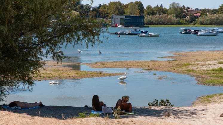 (260816) -- BELGRADE, Aug. 16, 2026 -- People rest on the bank of the Danube River in Belgrade, Serbia, on Aug. 16, 2026. Riverbed was exposed as the water level of the Danube River approached record-low by severe drought. (Photo by Xinhua) SERBIA-BELGRADE-DANUBE RIVER-DROUGHT WangxWei 