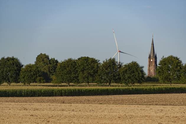 Weite Landschaft mit Windkraftanlage und Kirchturm hinter grünen Bäumen, Borken, Münsterland, Deutschland Wide landscape with wind turbine and church tower behind green trees, Borken, Münsterland, Germany Copyright: imageBROKER StephanxSuehling ibxssh18753974.jpg