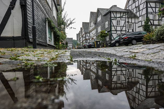 Wetterumschwung. Ein in den letzten Wochen eher seltenes Bild im Siegerland. Nach den trockenen heissen Tagen und Wochen startet die neue Woche nass und verhaeltnismaessig (verhältnismäßig) kuehl (kühl). Die Historische Altstadt von Freudenberg mit ihren Fachwerkhaeusern (Fachwerkhäusern). Die Haeuser (Häuser) spiegeln sich ein einer Pfuetze (Pfütze). Sommer im Siegerland am 17.08.2026 in Freudenberg Deutschland. *** Weather Change: A rare sight in the Siegerland region in recent weeks. After days and weeks of dry, hot weather, the new week is starting off wet and relatively cool. The historic old town of Freudenberg with its half-timbered houses. The haehouses are reflected in a puddle. Summer in the Siegerland region on August 17,